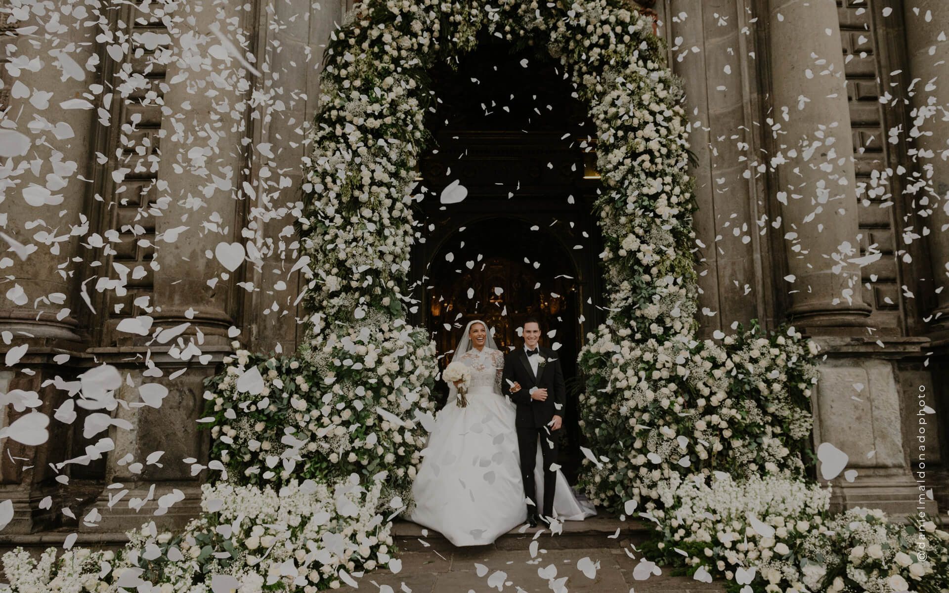 Couple under an arch of white flowers
